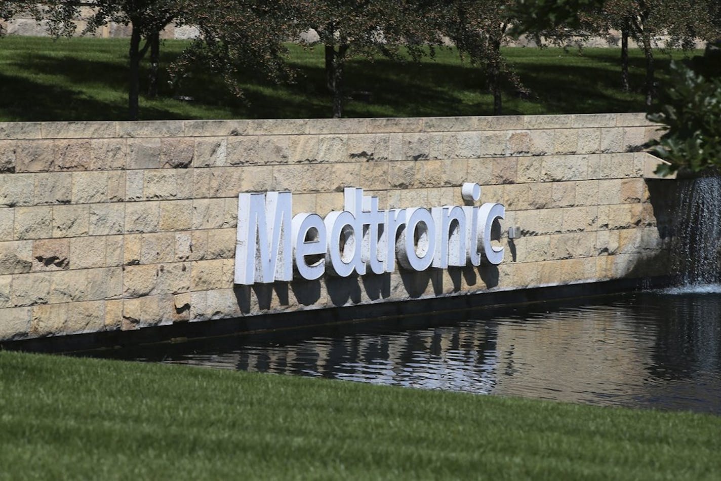 In this Aug. 29, 2019 photo, the Medronic logo is reflected in a lake at the Minnesota headquarters in Fridley, Minn. The legal headquarters of Medtronic is in Ireland. (AP Photo/Jim Mone)