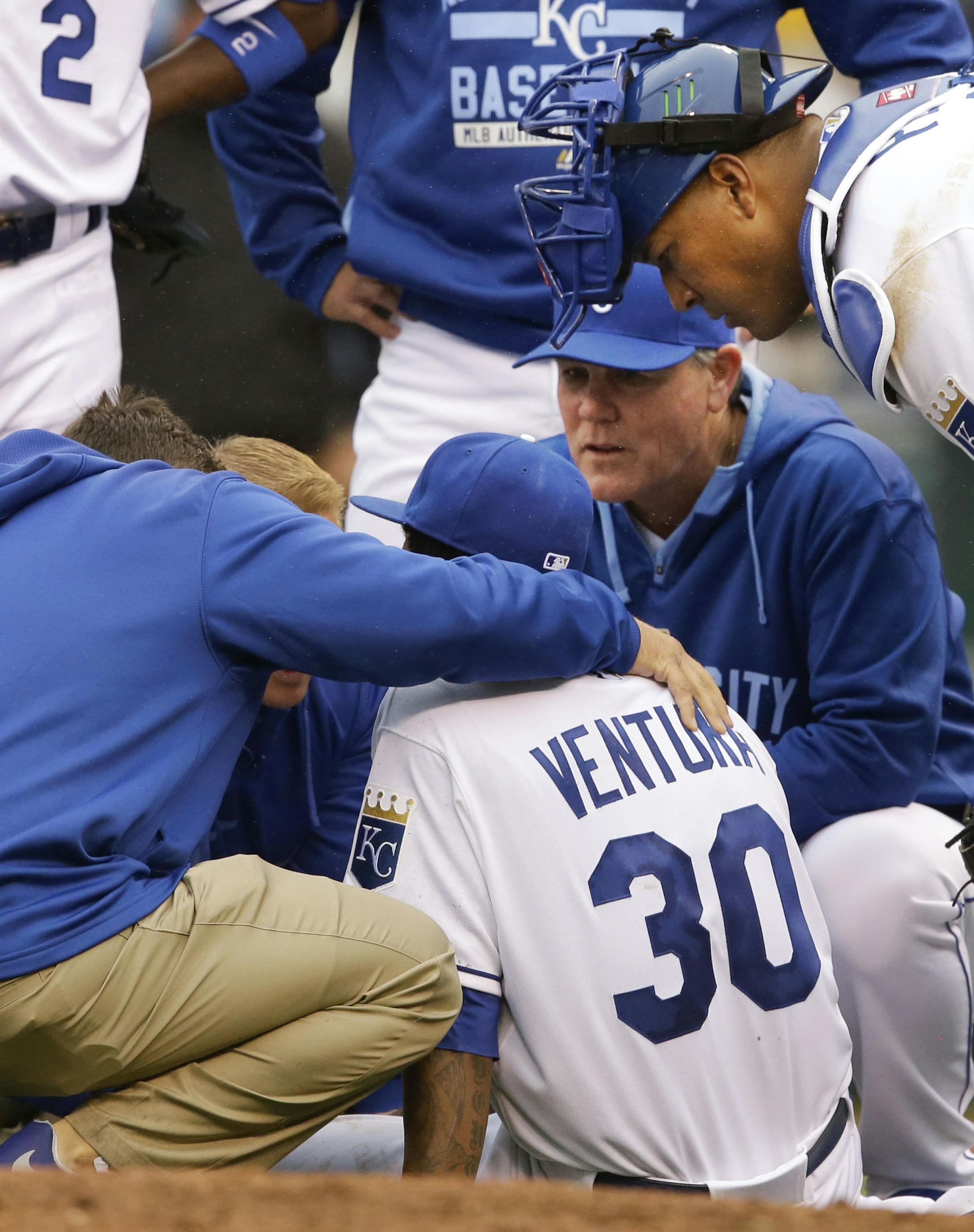 Kansas City Royals manager Ned Yost, back, and catcher Salvador Perez, right, check on starting pitcher Yordano Ventura (30) after an injury during the seventh inning of a baseball game against the Chicago White Sox at Kauffman Stadium in Kansas City, Mo., Monday, April 6, 2015. (AP Photo/Orlin Wagner)