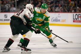 Wild forward Kirill Kaprizov (97) and Coyotes defenseman Janis Moser (90) fight for an airborne puck at Xcel Energy Center on Jan. 13, 2024 in St. Pau