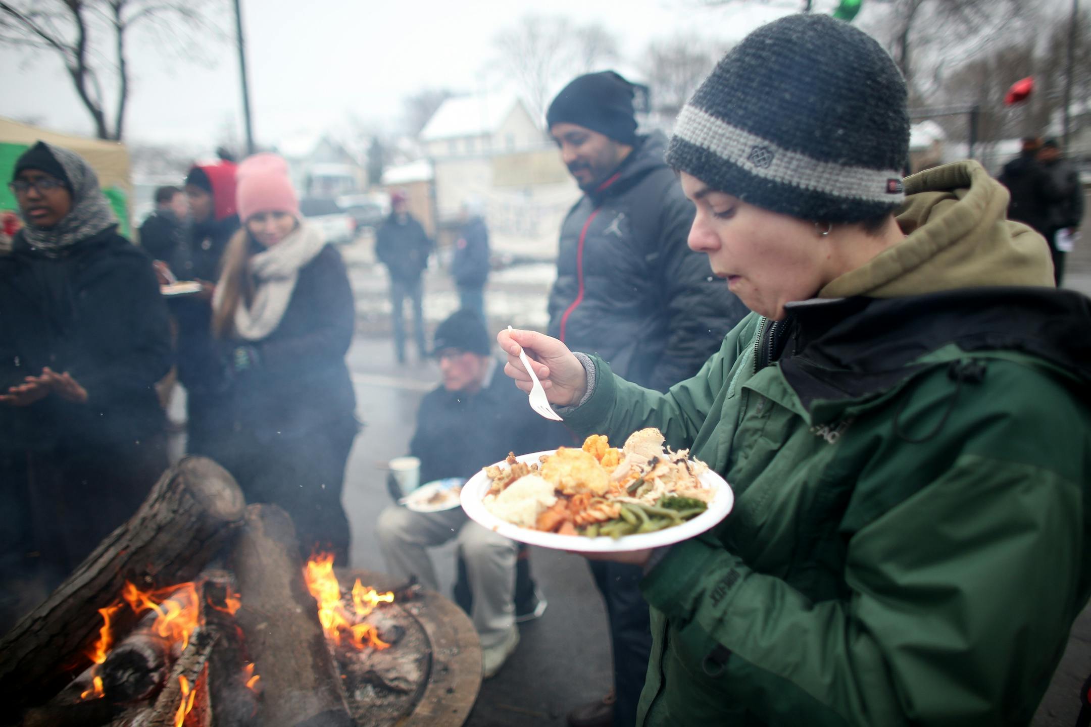 Ray Lockman ate her Thanksgiving dinner by the fire during BlackGiving event in front of the Minneapolis Fourth Precinct.