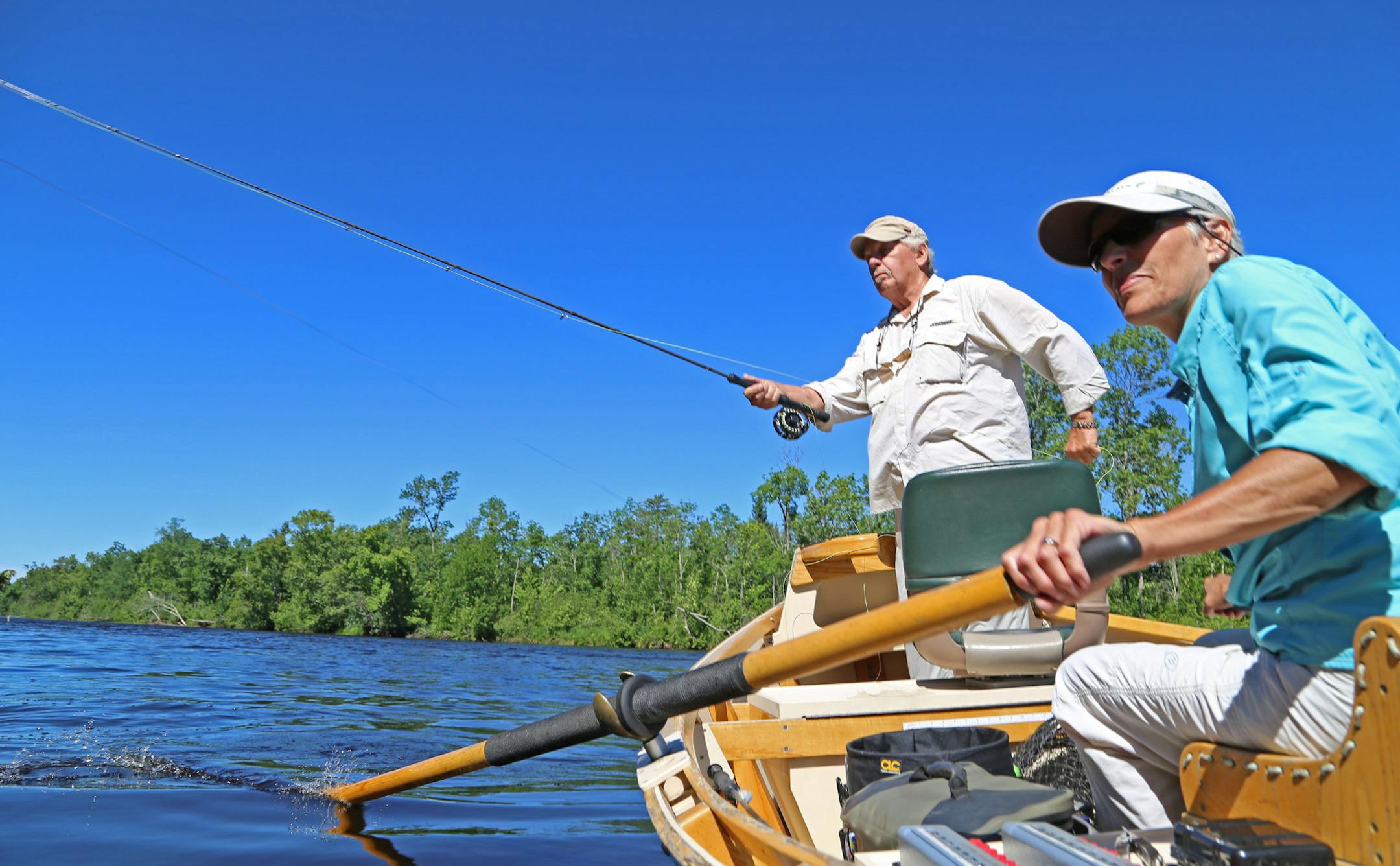 As guide Wendy Williamson steadies her drift boat in the currents of the Upper St. Croix River, angler Bob Nasby of St. Paul casts a fly near shore, looking for smallmouth bass.