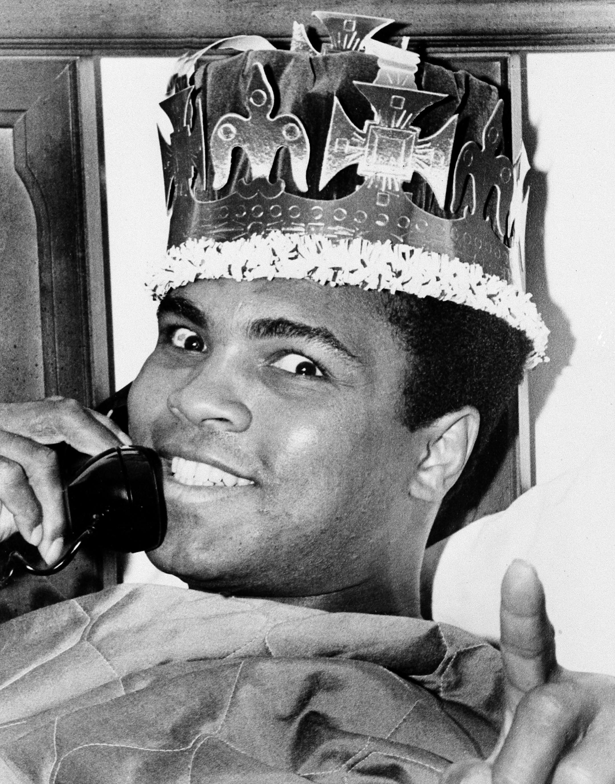 Muhammad Ali, in a jovial mood as his March 8 bout with Joe Frazier draws near, is seen speaking on the phone and wearing a king's crown, March 6, 1971, in Miami Beach. Ali and Frazier will meet on the 8th in New York's Madison Square Garden.