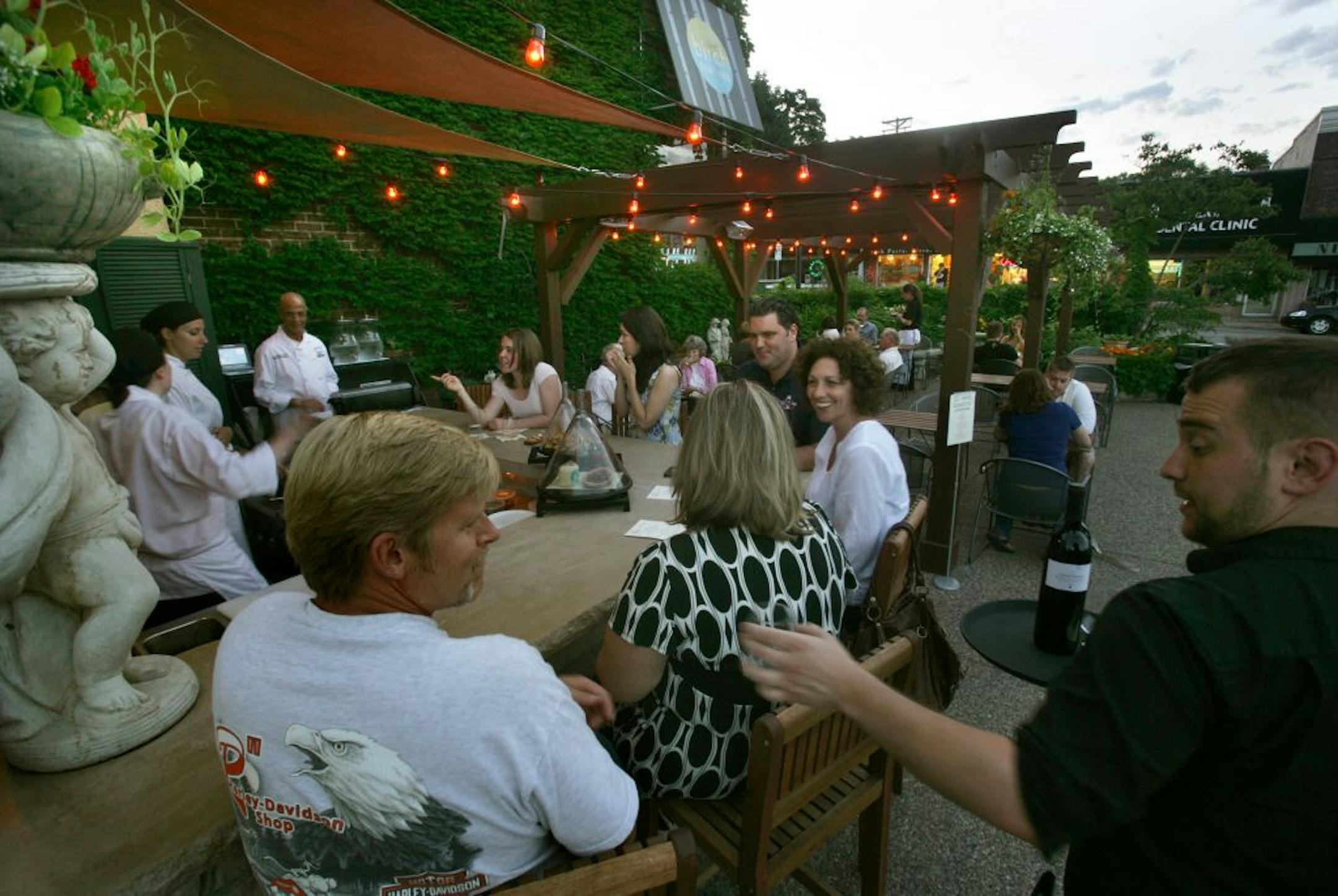 Broders Pasta Bar in Minneapolis, MN. Michael Hoolihan serves wine to Jay Krough (Mpls), Susan Smith (Mpls, black and white dress), Alayne Krough (Mpls,white dress), and Andrew Smulski (Pittsburg, Pa, black shirt). In background from left to right are sous chefs Laurel Somerville, Elizabeth Tinnucci, and Chef Michael Rostance. Talking to the chefs are Katie Mader (Mpls, pink shirt), and Anna Martignacco of St. Paul.bestmn2012 bestmn2012