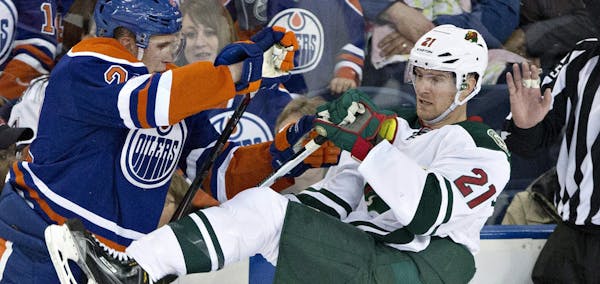 Minnesota Wild's Kyle Brodziak (21) is checked by Edmonton Oilers' Jeff Petry (2) during the second period of an NHL hockey game Friday, Feb. 20, 2015
