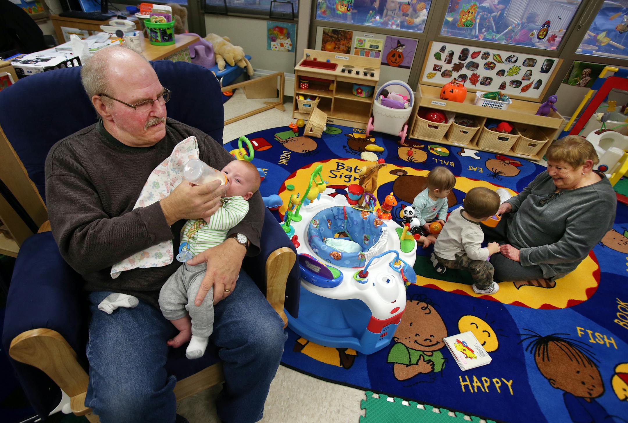 Senior Jim Saefke, a City Council member, wanted to join the rocking chair crew. Jim Saefke rocks Sorkin (the baby, first name only) at the Fridley Community Center and Senior volunteer, Barb Miller plays with Mila and Austin on the floor in Fridley, MN on October 14, 2013. ] JOELKOYAMA‚Ä¢joel koyama@startribune