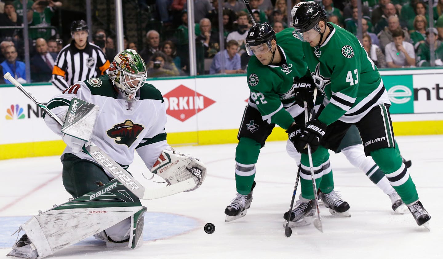 Minnesota Wild goalie Devan Dubnyk looks to gather up the puck next to Dallas Stars attackers Colton Sceviour (22) and Valeri Nichushkin (43) during the first period in Game 1 of a first-round NHL hockey Stanley Cup playoff series Thursday, April 14, 2016, in Dallas. (AP Photo/LM Otero)