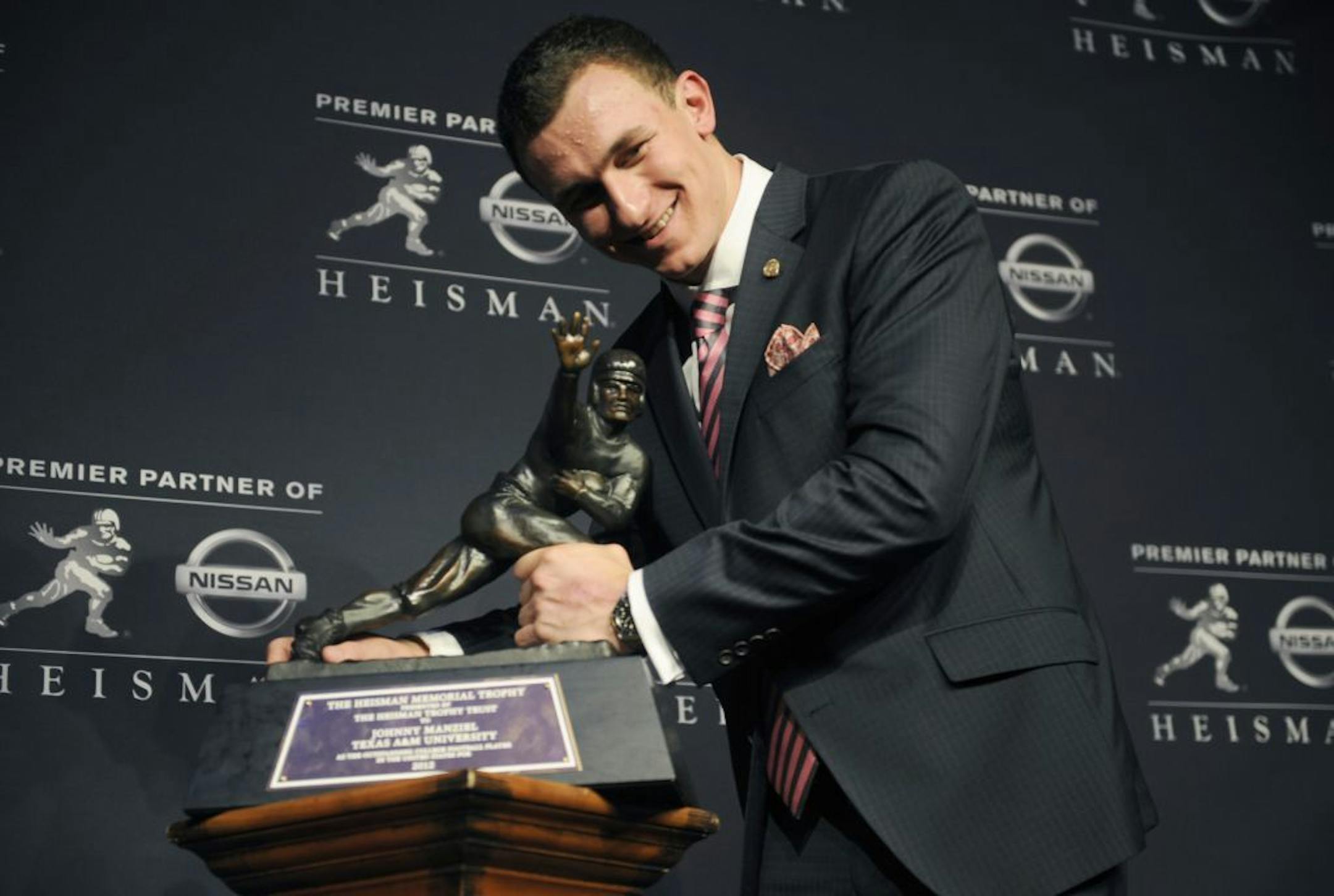 Texas A&M quarterback Johnny Manziel poses with the Heisman Trophy after becoming the first freshman to win the award, Saturday, Dec. 8, 2012, in New York.