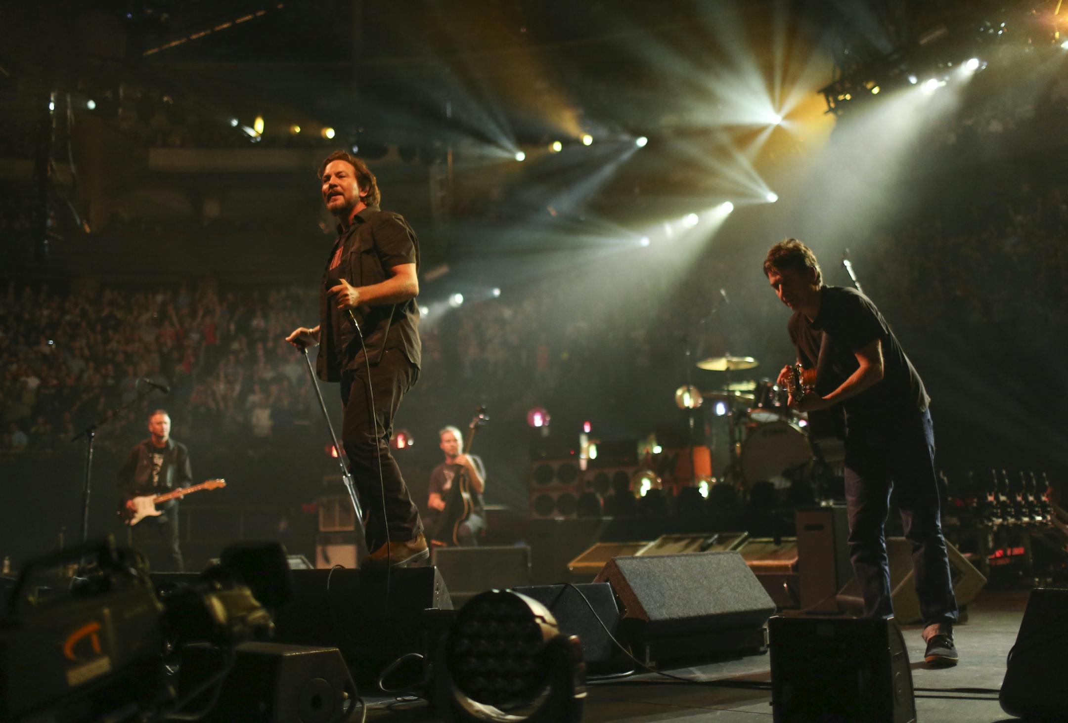 Pearl Jam's singer, Eddie Vedder, stood on a monitor early in the band's set Sunday night at Xcel Energy Center. The others are, from left, guitarist Mike McCready, bassist Jeff Ament, and guitarist Stone Gossard.