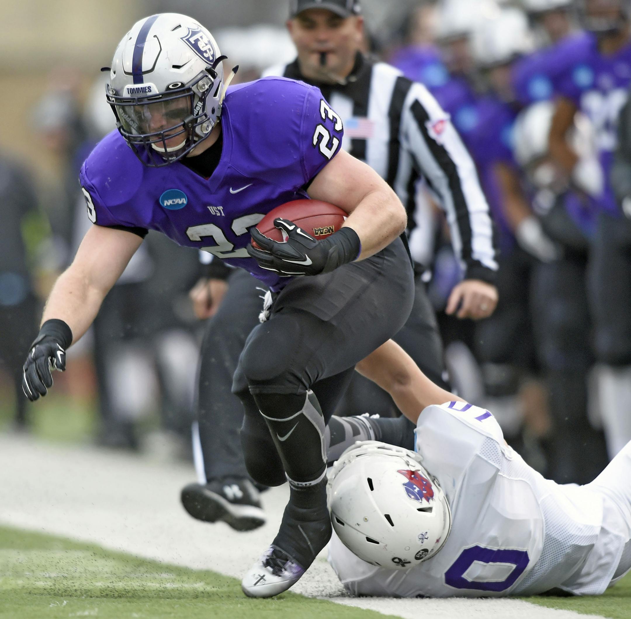 Linfield middle linebacker Skylor Elgarico (10) pulls St. Thomas running back Jordan Roberts (23) out of bounds during the first quarter during a Division III NCAA college football semifinal game on Saturday, Dec. 12, 2015, in St. Paul, Minn. (AP Photo/Hannah Foslien)