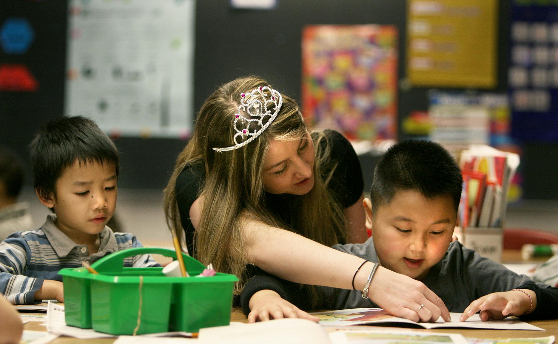 Teacher Melanie Lovell helped Damian Yang, 6, left, and Chue Her, 7, during reading time at Eastern Heights Elementary. Lovell wears the crown when she doesn't want students to interrupt her, unless it's an emergency.