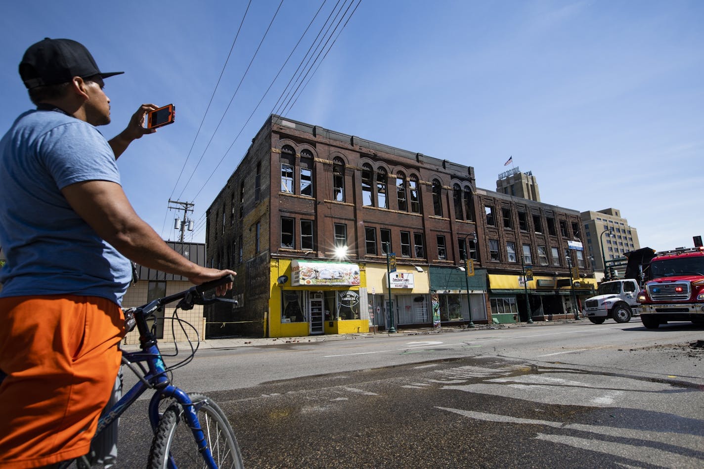 A passerby takes cell phone photos of the aftermath of a three-alarm fire at Lake Street and Chicago Avenue.