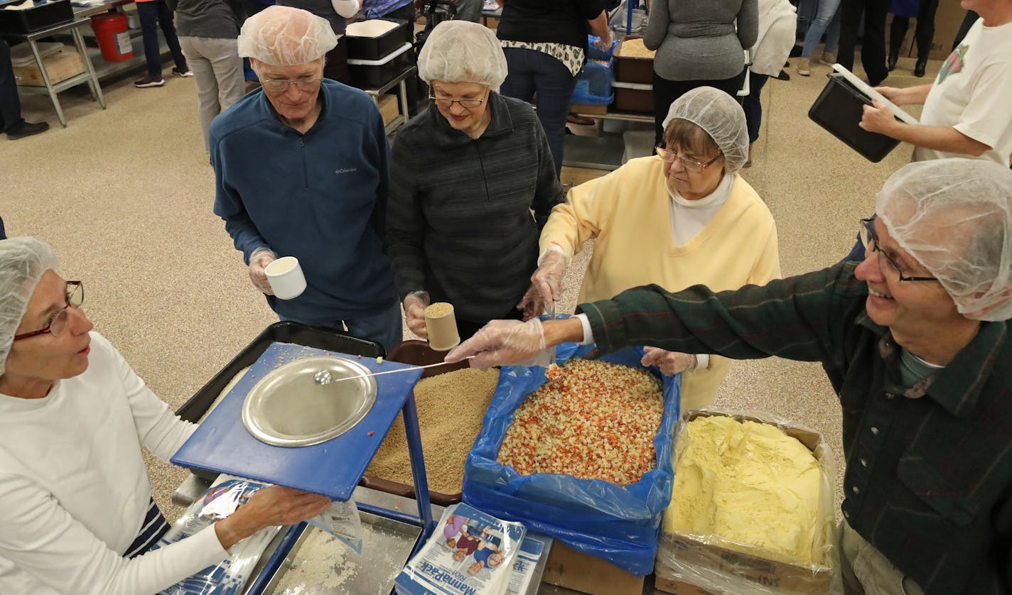 Several groups gathered at the workstation tables inside Feed My Starving Children in Coon Rapids on Give To The Max day.