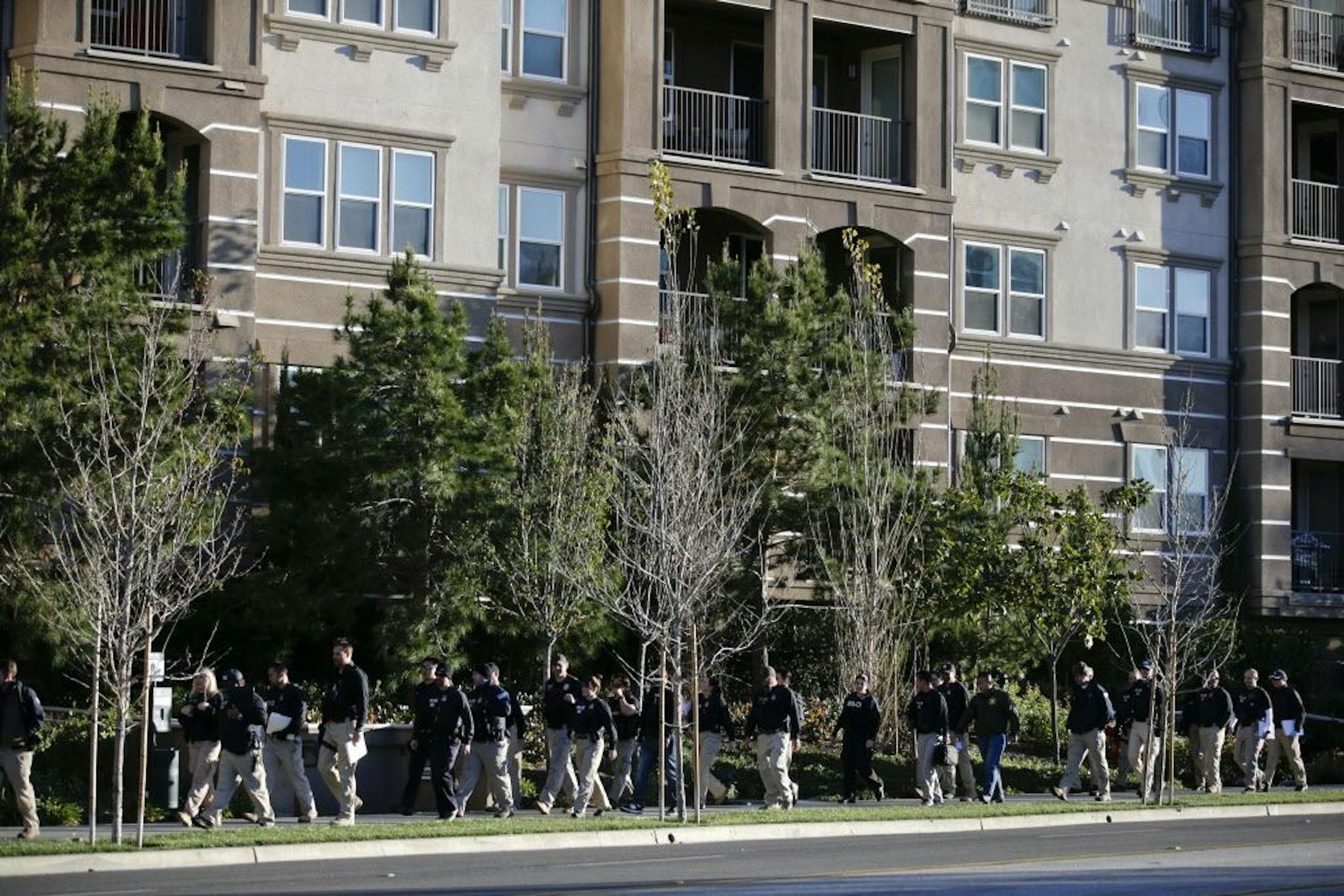 Federal agents walk along a sidewalk outside an upscale apartment complex, Tuesday, March 3, 2015, in Irvine, Calif.