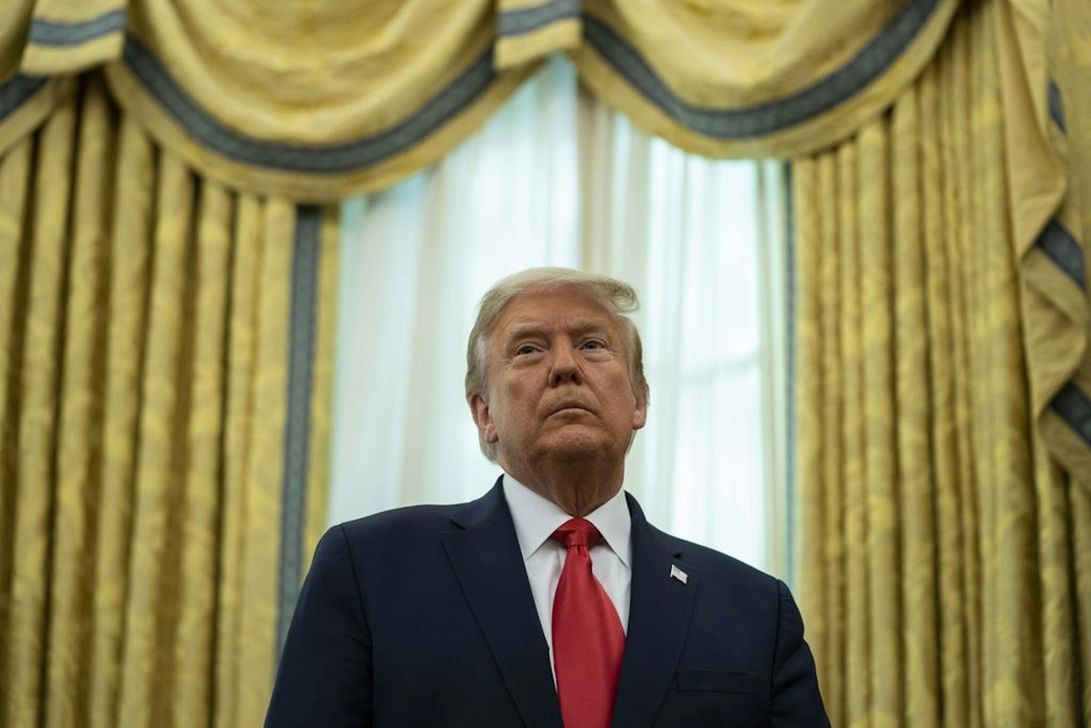 President Donald Trump listens during a ceremony to present the Presidential Medal of Freedom to former football coach Lou Holtz, in the Oval Office of the White House, Thursday, Dec. 3, 2020, in Washington.
