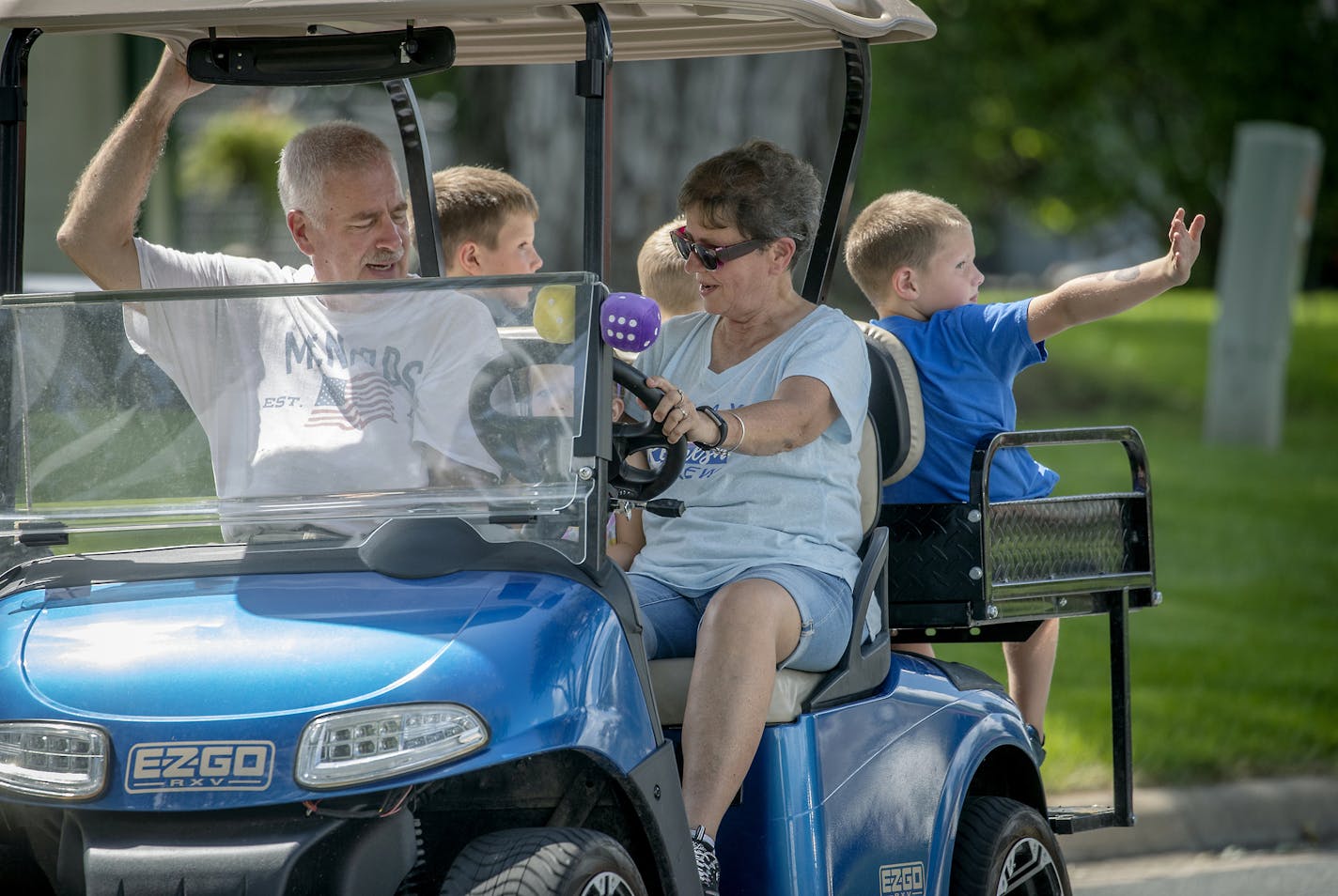 Jo Ann Monnens picked up her husband Paul, as she gave her grandchildren, including Kaia, 3, front, Parker, back left, Jameson, 5, center, and Isaac, 7, a ride on her golf cart through her Shakopee neighborhood, Wednesday, August 15, 2019. Monnens is one of a growing number of golf cart enthusiasts in the suburbs. ] ELIZABETH FLORES &#x2022; liz.flores@startribune.com