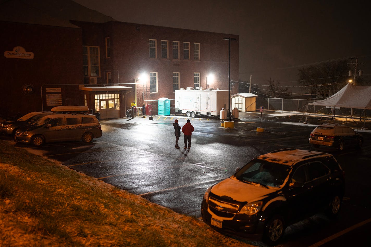 Anne Romberg, a Safe Bay staffer, left, visited with Erik Lind as she checked him in after he arrived in his vehicle to spend the night Monday night, October 30, 2023 in Duluth. At night, the parking lot of the Damiano Center becomes Safe Bay, a place where unhoused people can sleep in their vehicles without fear for their safety. A mobile hygiene trailer has showers and bathrooms for people to use before they settle in for the night. Safe Bay is an initiative of Stepping On Up, a coalition of Duluth social service organizations, many of which are housed in the Damiano Center. ] JEFF WHEELER • Jeff.Wheeler@startribune.com