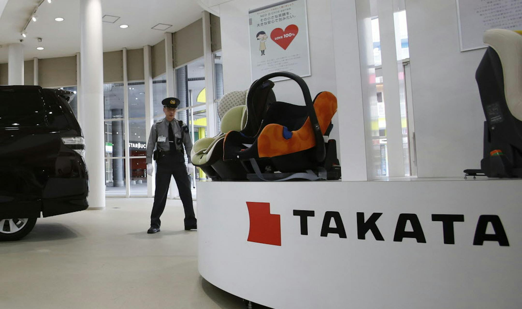 FILE - In this Nov. 6, 2014 file photo, a security guard stands by child seats, manufactured and displayed by Takata Corp. at an automaker's showroom in Tokyo. Japanese automaker Honda Motor Co. expanded its recalls related to defective air bags on Thursday, Nov. 13, 2014, saying a driver in Malaysia died in an air bag-linked accident earlier this year. The air bags, made by Japanese manufacturer Takata Corp., have faulty inflators that can explode, hurling shrapnel toward drivers and passengers