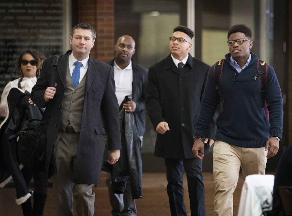 Lawyer Ryan Pacyga, left, walks with Minnesota football players Carlton Djam, from right, and Antoine Winfield, Jr, accompanied by his father, former 