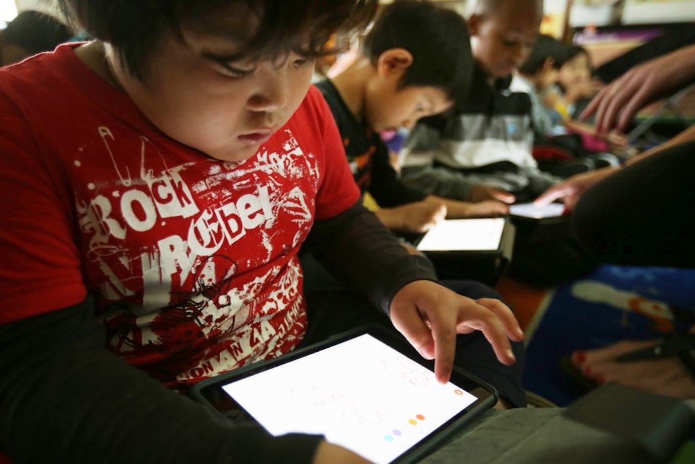 Kindergarteners Aye Mya Thein left Jaw Kaw Htoo and Calvin Marshall students at Mississippi Creative Arts School worked on math skills on an iPad Wednesday May 20, 2015 in St. Paul, MN. A year ago, St. Paul set out to be the largest district in the state to put iPads in the hands of all students, and at the project's midpoint, there is evidence it is spurring student engagement in what the district has described as a "year of exploration." But the initiative also has triggered budget tensions, a