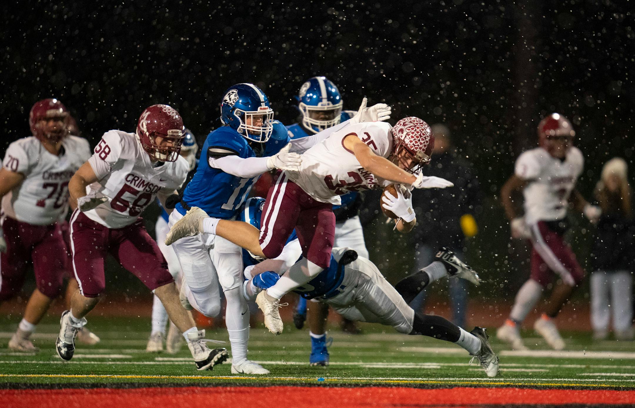 Maple Grove's Tanner Albeck (35) was tripped up by Woodbury's Joey Gerlach (6) with help from Garrett Smith (11) during a first quarter run Thursday, Nov. 11, 2021 in Eden Prairie. The Maple Grove Crimson faced the Woodbury Royals in a MSHSL Class 6A football state tournament quarterfinal game Thursday, Nov. 11, 2021 night at Eden Prairie High School in Eden Prairie. ] JEFF WHEELER • Jeff.Wheeler@startribune.com