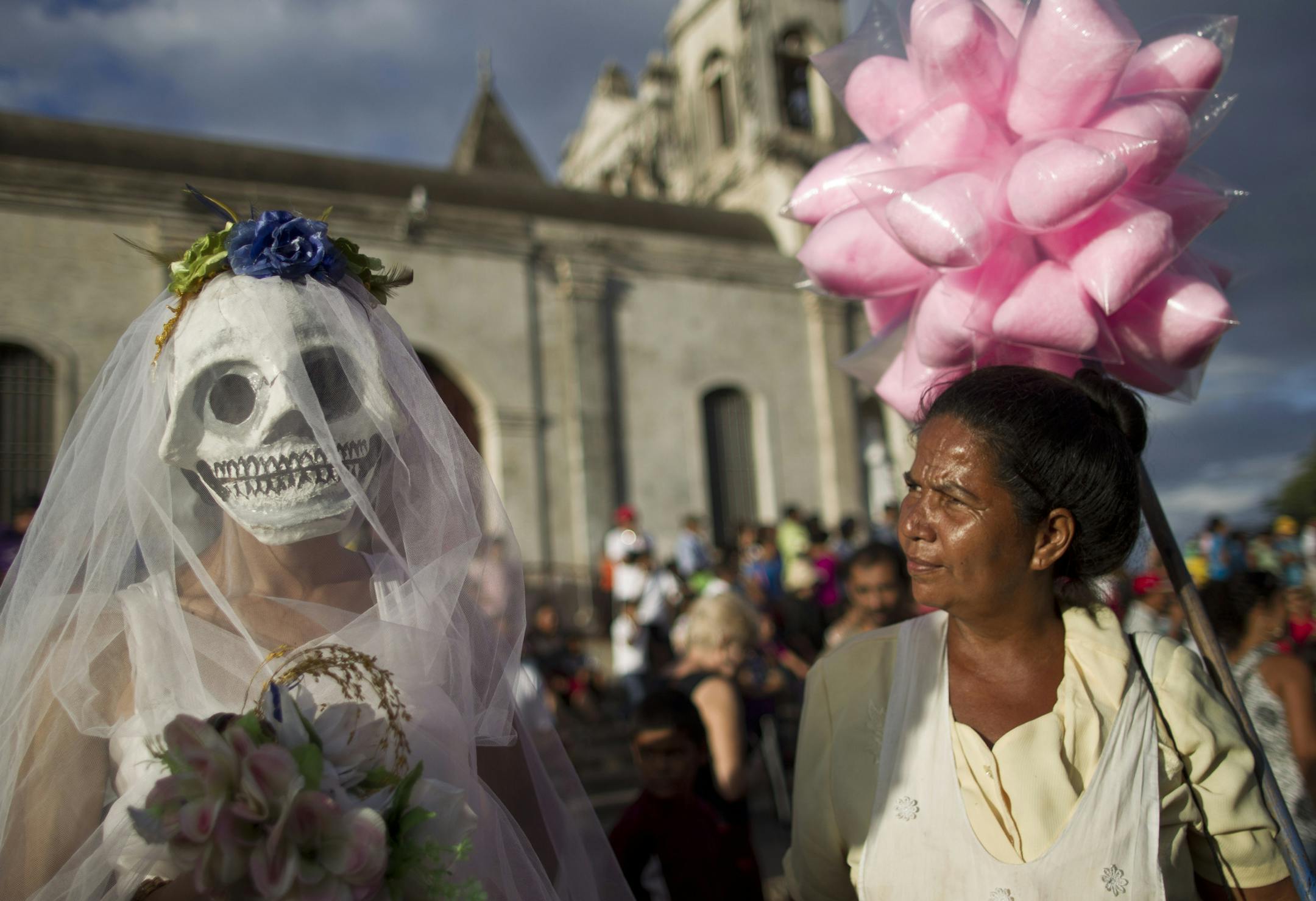 A street vendor, right, looks at a disguised reveler during celebrations marking the 9th International Poetry Festival honoring Nicaraguan poet, priest and former Nicaragua's Culture Minister, Ernesto Cardenal, not in picture, in Granada, Nicaragua, Wednesday, Feb 20, 2013. The festival is attended by more than 300 poets from some 60 countries. (AP Photo/Esteban Felix)