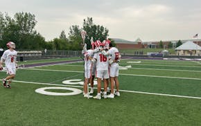 Stillwater players huddle before their boys lacrosse state semifinal against East Ridge.