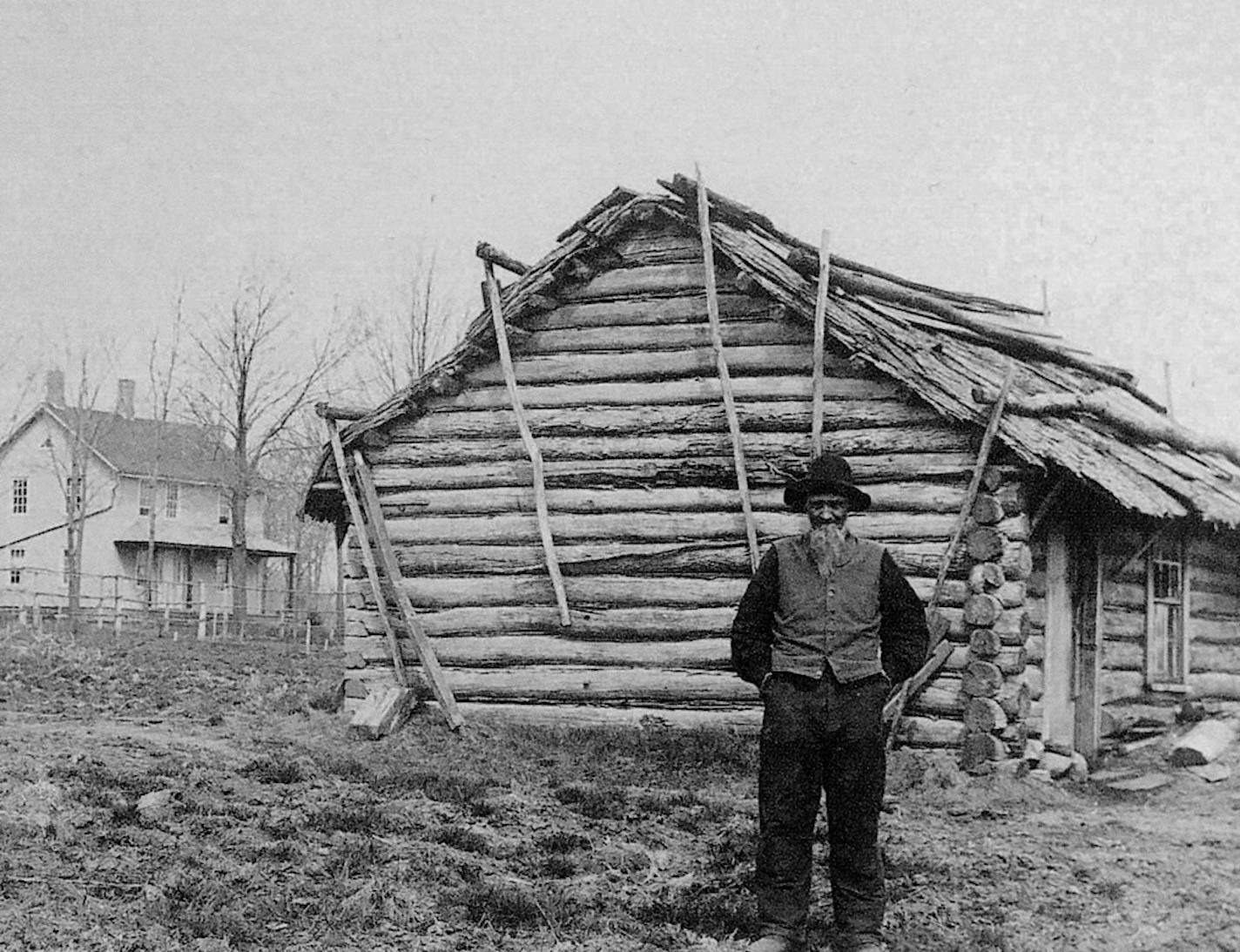 Andrew Peterson in 1885, standing by the log cabin he first lived in on his farm in Waconia. In the background stands the later farmhouse that still exists.