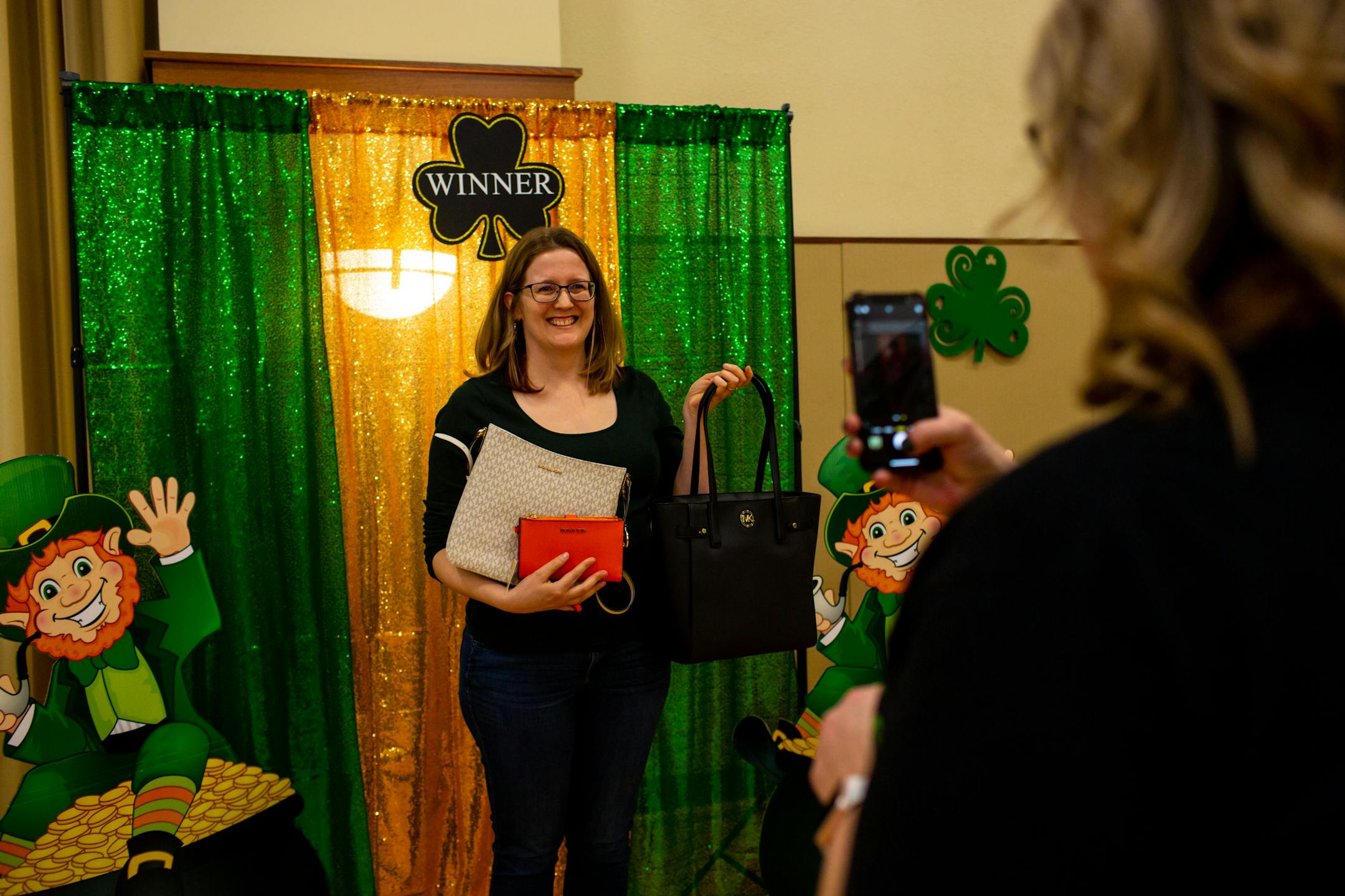 Jill Schmidt poses with her new Michael Kors set of purses after winning during Designer Purse & Gun Bingo.