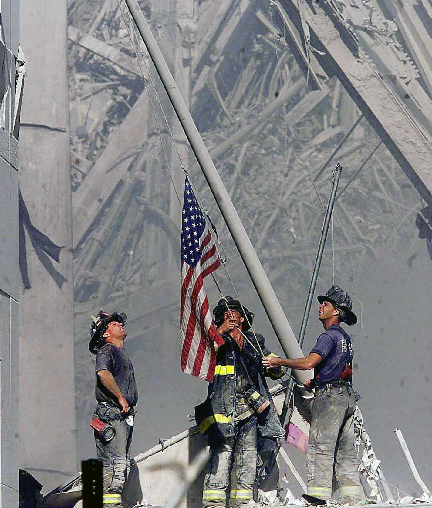 ** FOR USE AS DESIRED, PHOTOS OF THE DECADE ** FILE - Brooklyn firefighters George Johnson, left, of ladder 157, Dan McWilliams, center, of ladder 157, and Billy Eisengrein, right, of Rescue 2, raise a flag at the World Trade Center in New York, in this Sept. 11, 2001 file photo, as work at the site continues after hijackers crashed two airliners into the center. In the most devastating terrorist onslaught ever waged against the United States, knife-wielding hijackers crashed two airliners into