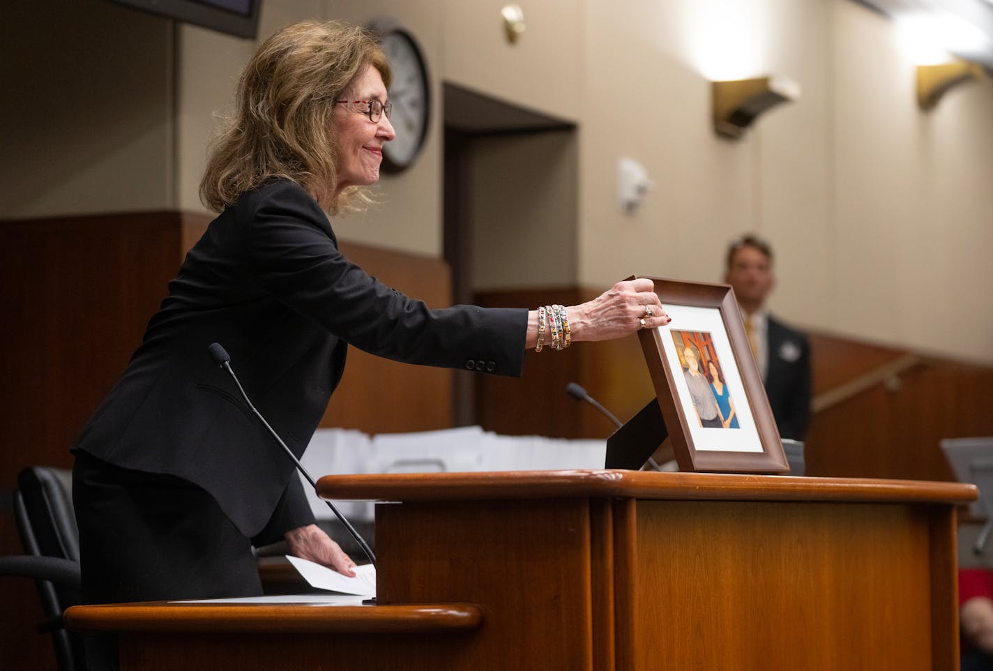 Ellen Kennedy retrieves a photo of her late husband, Leigh Lawton, who died from cancer in 2022, from the podium after speaking in support of the End-of-Life Options Act during a hearing in the Minnesota House Health Finance & Policy Committee Thursday, Jan. 25, 2024, at the State Office Building in St. Paul, Minn.     ]
ALEX KORMANN • alex.kormann@startribune.com