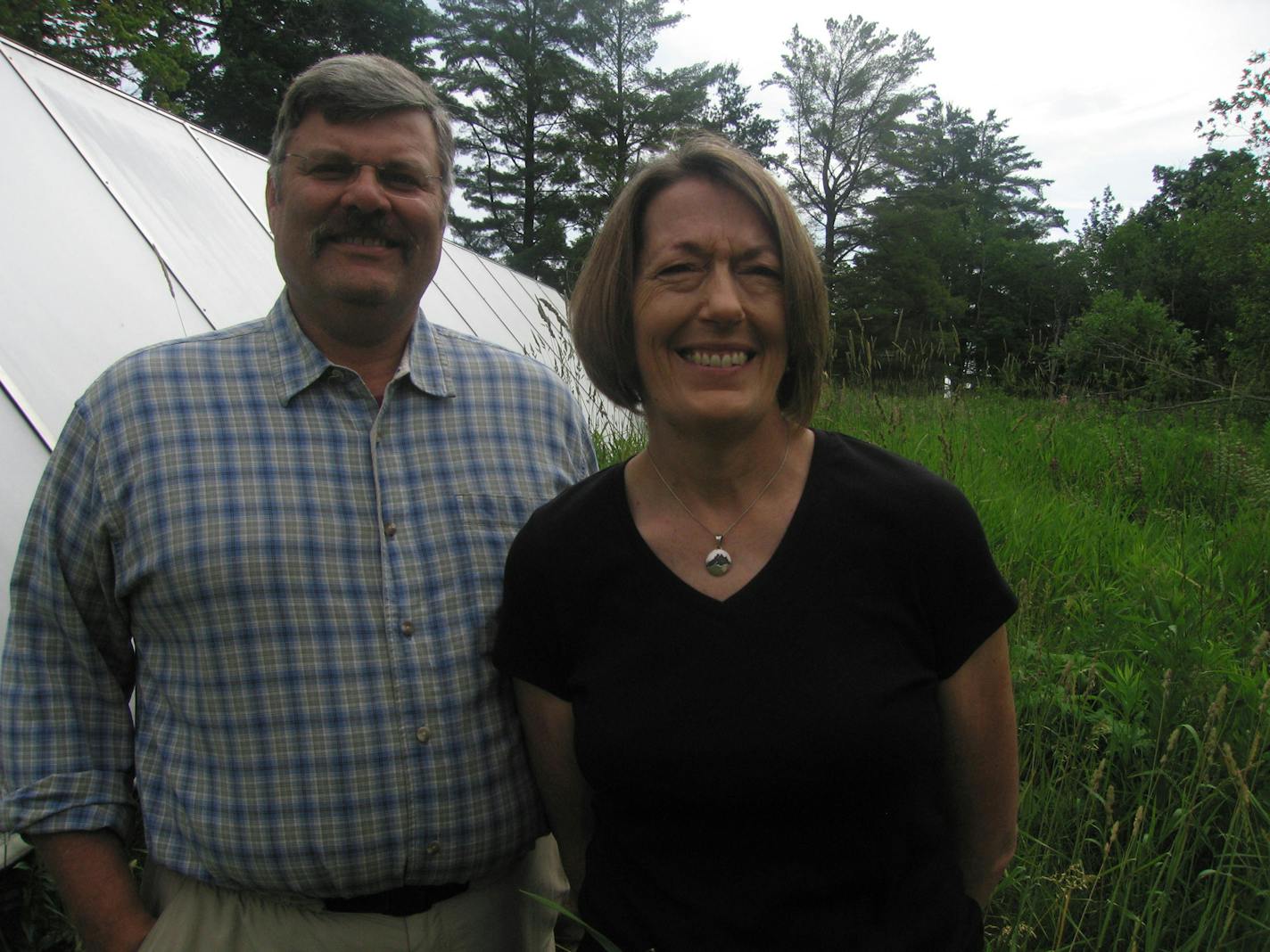 Steve and Nancy Sandstrom, owners of Pinehurst Inn at Pikes Creek, stand in front of the solar panels that heat much of the water used by their bed and breakfast.