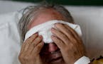 A man places a cold compress on his forehead while battling the flu at a hospital in Georgia. 
