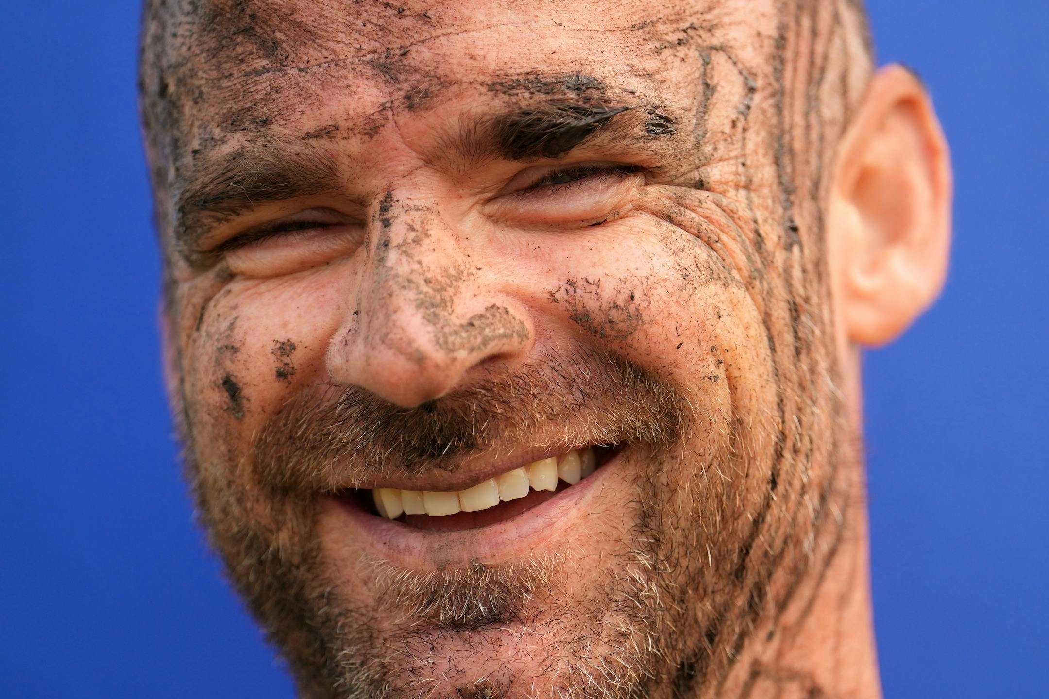 Alex Hae stands covered in mud near the finish line after running the Minneswashta Mud Run.