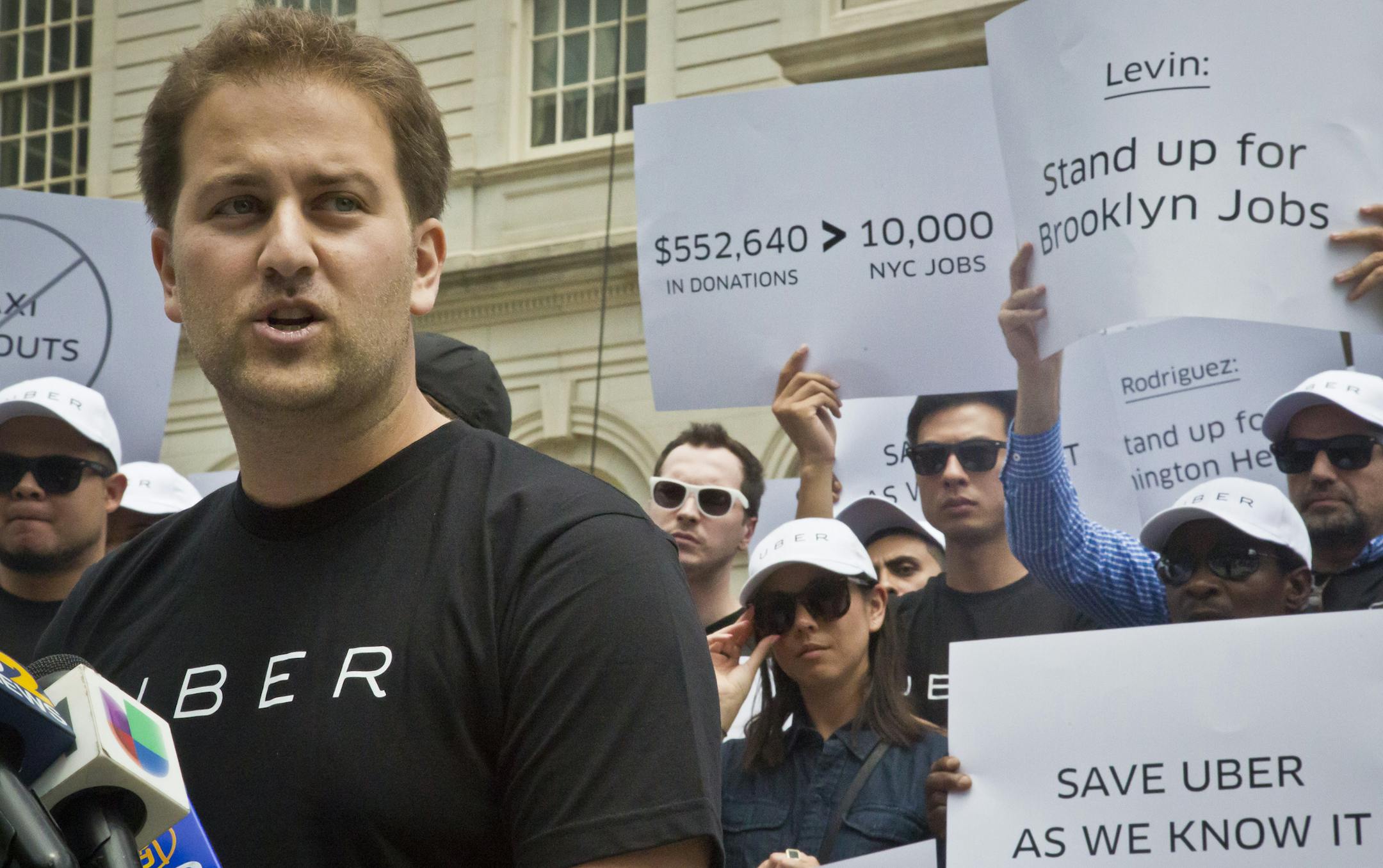 Josh Mohrer, left, New York's general manager for Uber, speaks during a press conference rally outside City Hall, while inside lawmakers hold a hearing on the growth of the For-Hire-Vehicle (FHV) industry with a focus on Uber, Tuesday, June 30, 2015, in New York. A new bill proposes a growth cap on vehicles for hire while New York City studies how e-hail companies are affecting traffic. (AP Photo/Bebeto Matthews)
