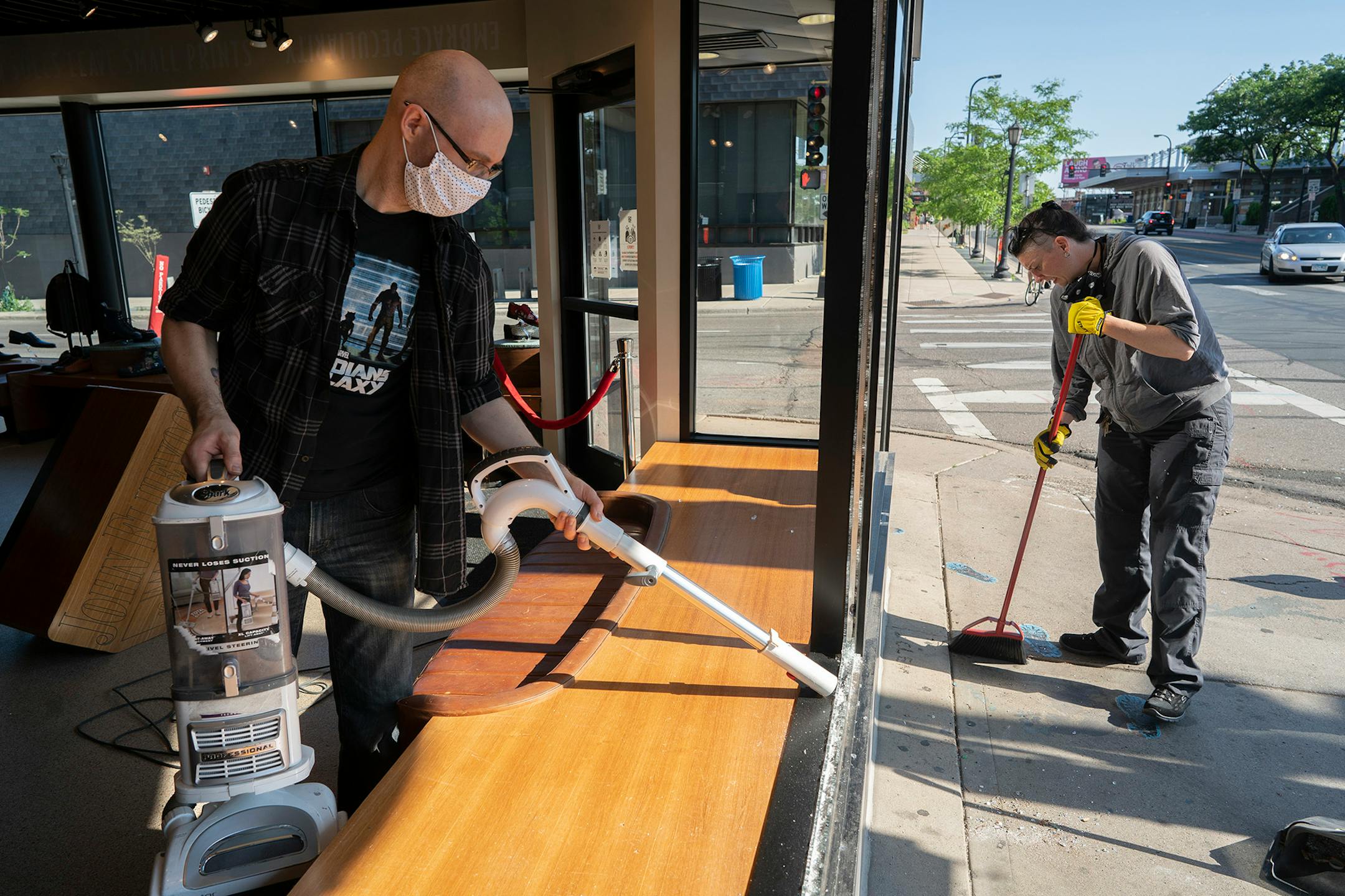 Jeff Neppl, left, and Megan Culverhouse, employees at John Fluevog shoe store, cleaned up broken glass from a window that was hit by gunfire from an early morning shooting.