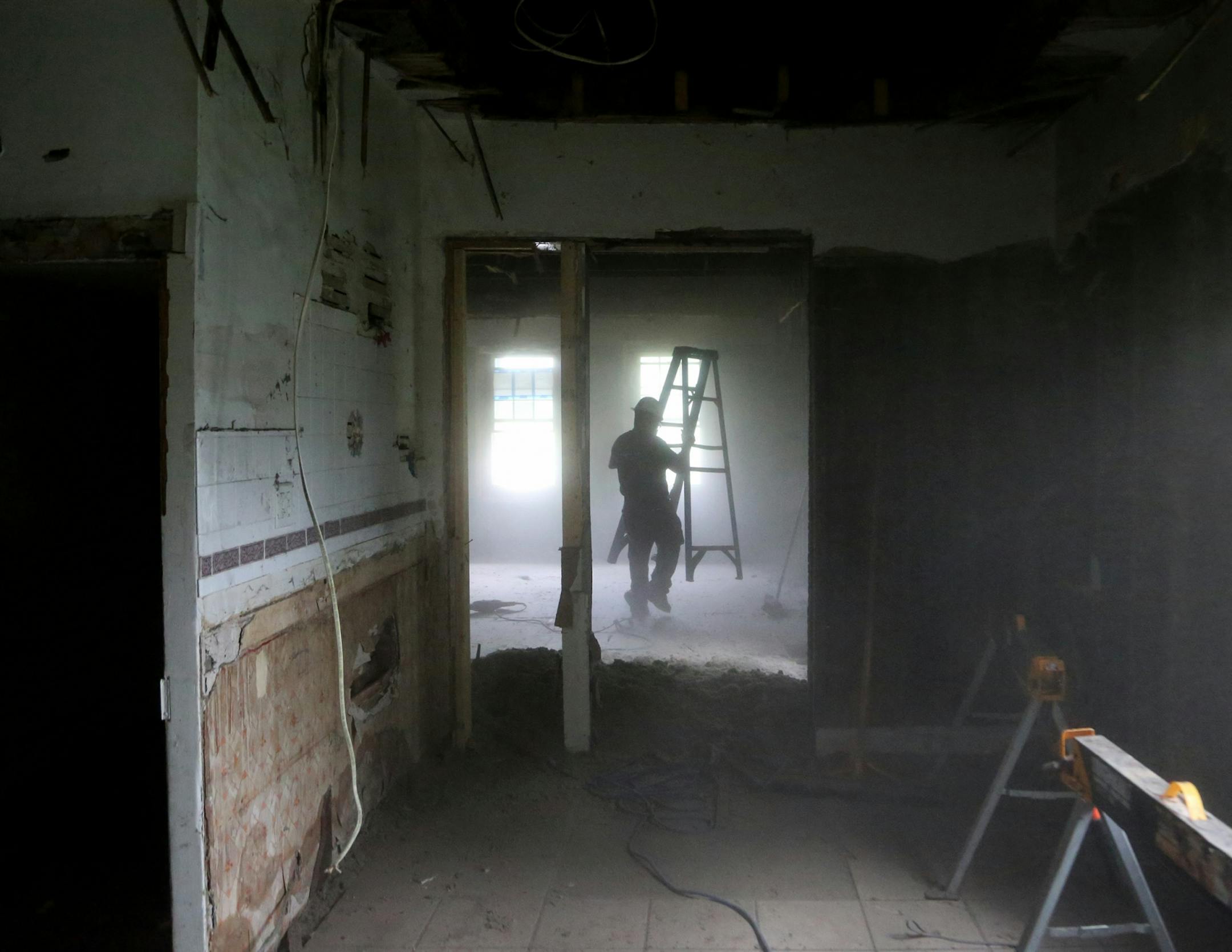 Dust from insulation in a ceiling being torn down obscures Josh Stewart, crew-chief-in-training for Better Homes Minnesota, a non-profits that assists men in the community in gaining employment while helping protect the environment, as a home was disassembled and seen Tuesday, July 18, 2017, in Roseville, MN.