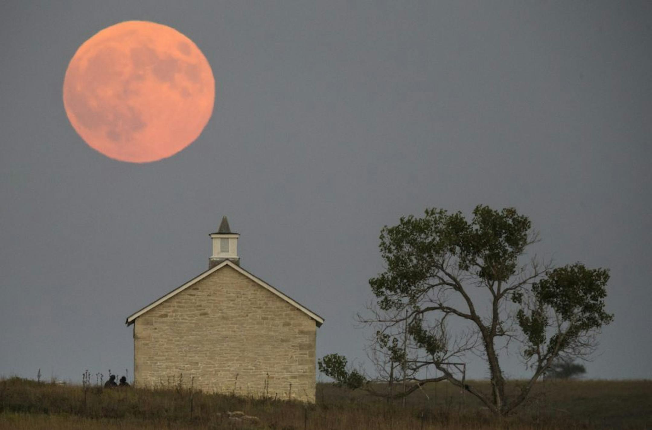 A super moon rises over the Lower Fox Creek School near Strong City, Kan., Sunday, Sept. 27, 2015. It was the first time Sunday since 1982 that a total lunar eclipse was combined with a supermoon. (Travis Heying/The Wichita Eagle via AP) LOCAL TELEVISION OUT; MAGS OUT; LOCAL RADIO OUT; LOCAL INTERNET OUT; MANDATORY CREDIT