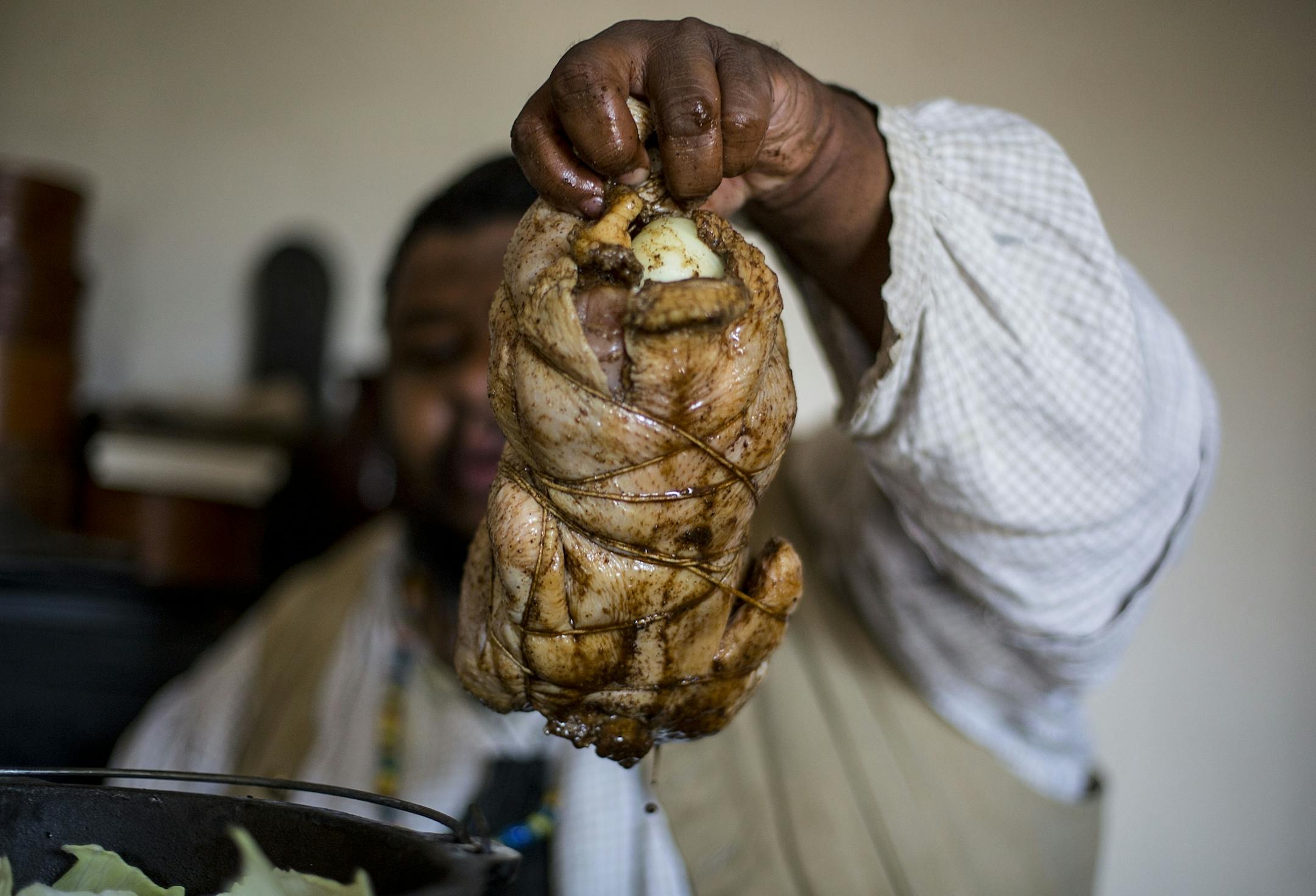 Michael Twitty binds the chicken together with twine before covering it in cabbage leaves to cook.