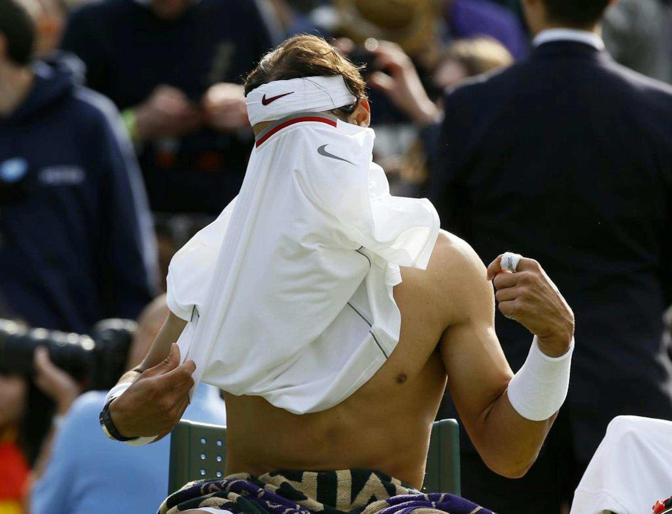 Rafael Nadal of Spain changes shirt during a break in his Men's first round singles match against Steve Darcis of Belgium at the All England Lawn Tennis Championships in Wimbledon, London, Monday, June 24, 2013.
