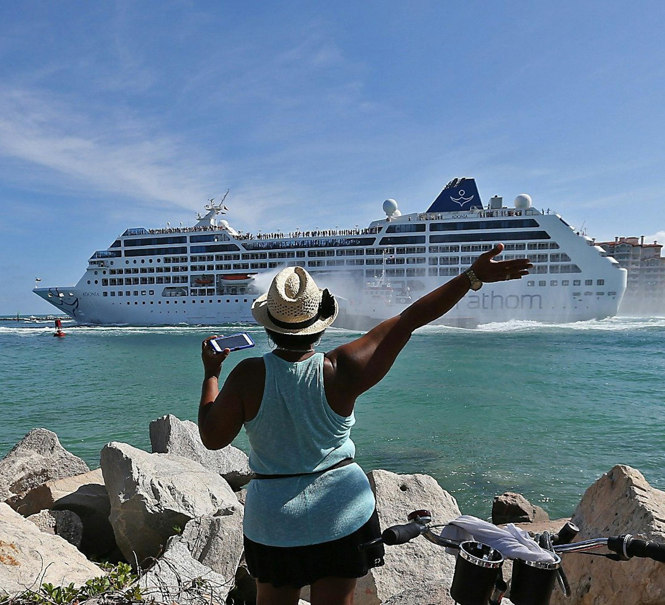 A woman from Cuba waves Adonia leaves port in Miami, Sunday, May 1, 2016, en route to Cuba. After a half-century of waiting, passengers finally set sail on Sunday from Miami on an historic cruise to Cuba. Carnival's Cuba cruises, operating under its Fathom band, will visit the ports of Havana, Cienfuegos and Santiago de Cuba. (Patrick Farrell/The Miami Herald via AP) MAGS OUT; MANDATORY CREDIT