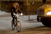 A bicyclist travels through light snow Tuesday morning along Portland Avenue South near downtown Minneapolis.