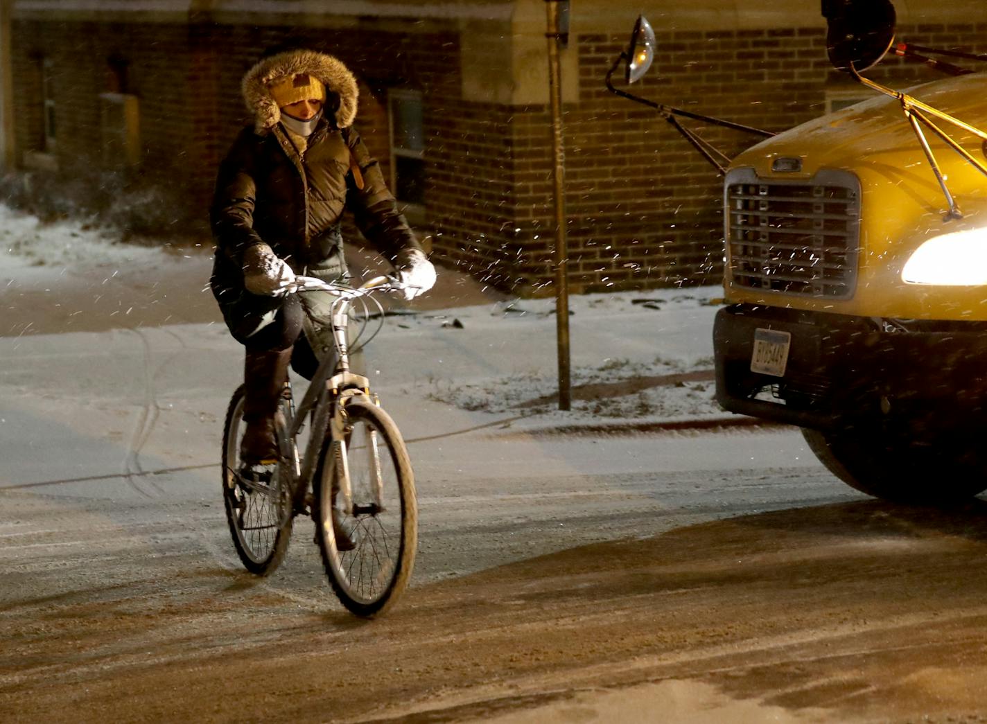 A bicyclist travels through light snow Tuesday morning along Portland Avenue South near downtown Minneapolis.