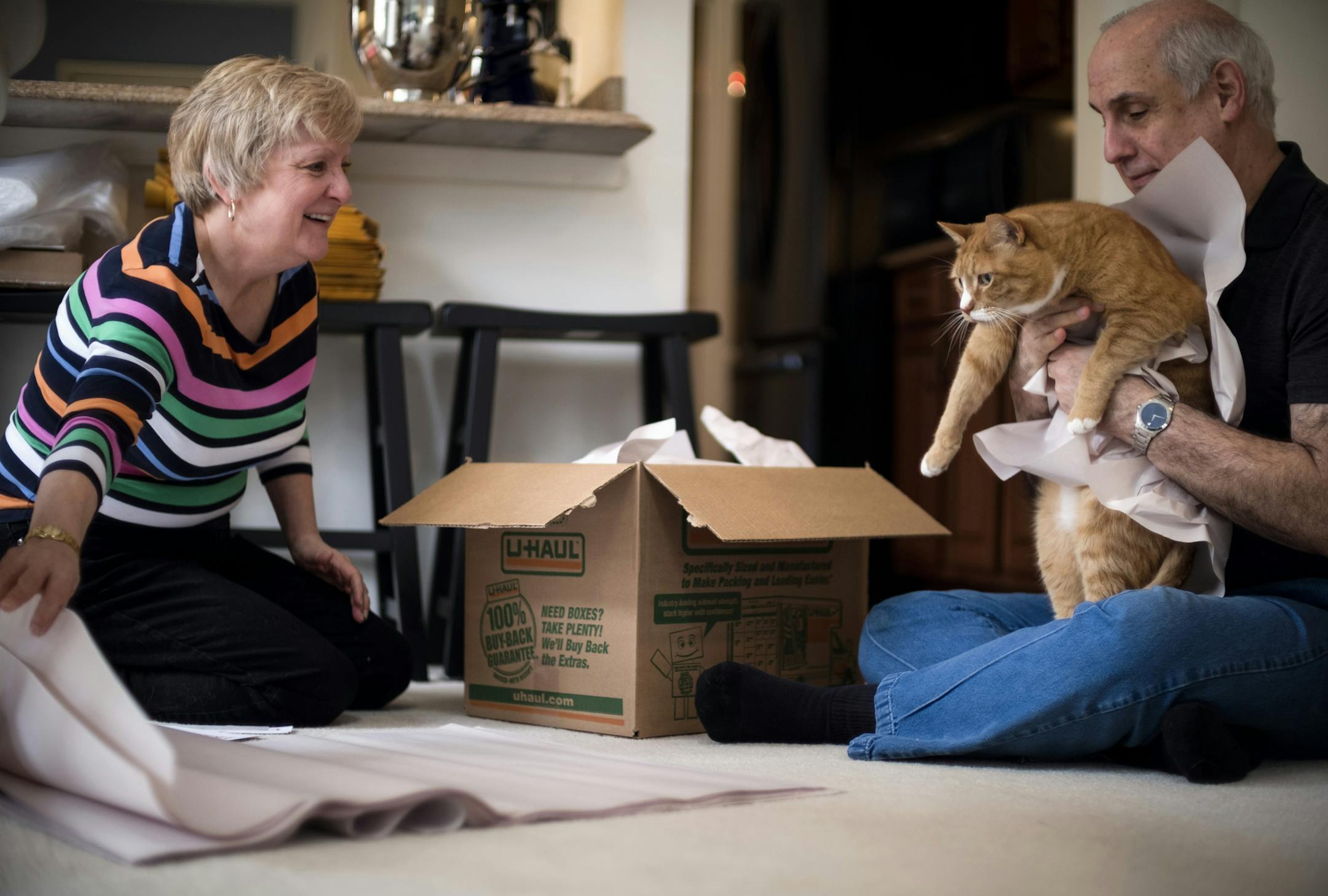 Larry Gomberg (right) pretends to pack their cat into a moving box as he and Martha Powers box up some of their last kitchen items at their Fairfax, Va., home before moving to their new retirement home about an hour away in Lake Frederick, Va. MUST CREDIT: photo for The Washington Post by J. Lawler Duggan.
