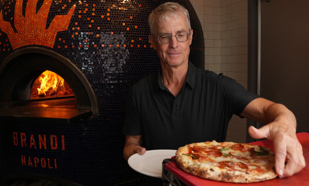 Punch pizza co-owner John Puckett dishes up a pizza as he stands for a portrait Friday, Aug. 4, at their location on Grand Avenue in St. Paul, Minn.