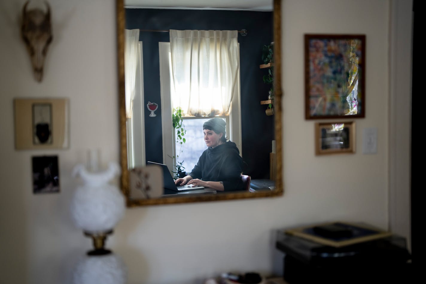 A photo of Emily Mohrbacher in her home office working on a laptop.