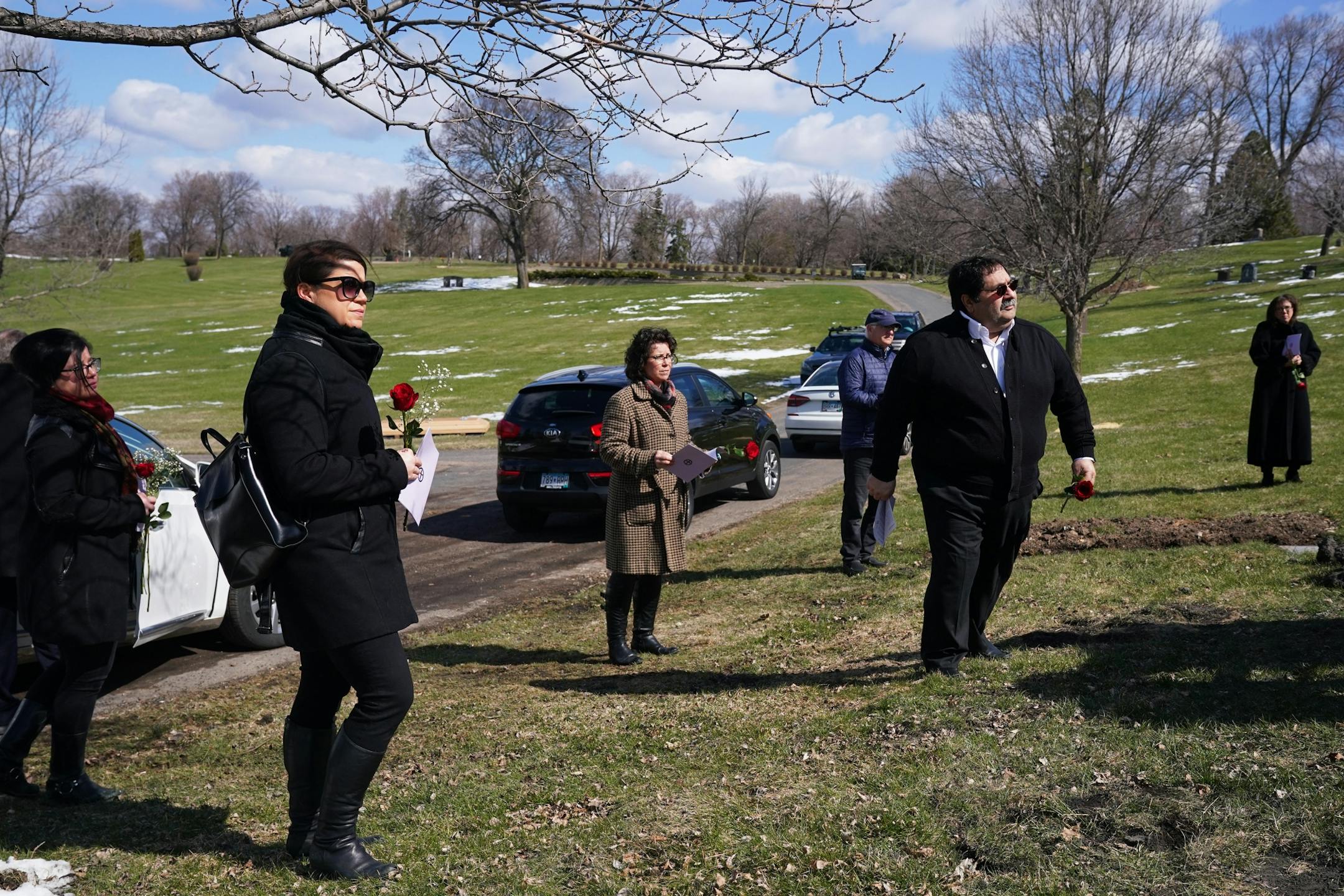 Family and friends including granddaughter Elianne Farhat, second from left, worked to keep the recommended distancing from one another during funeral services for Elie Farhat, who recently died of COVID-19 at the age of 92, at his gravesite Thursday.