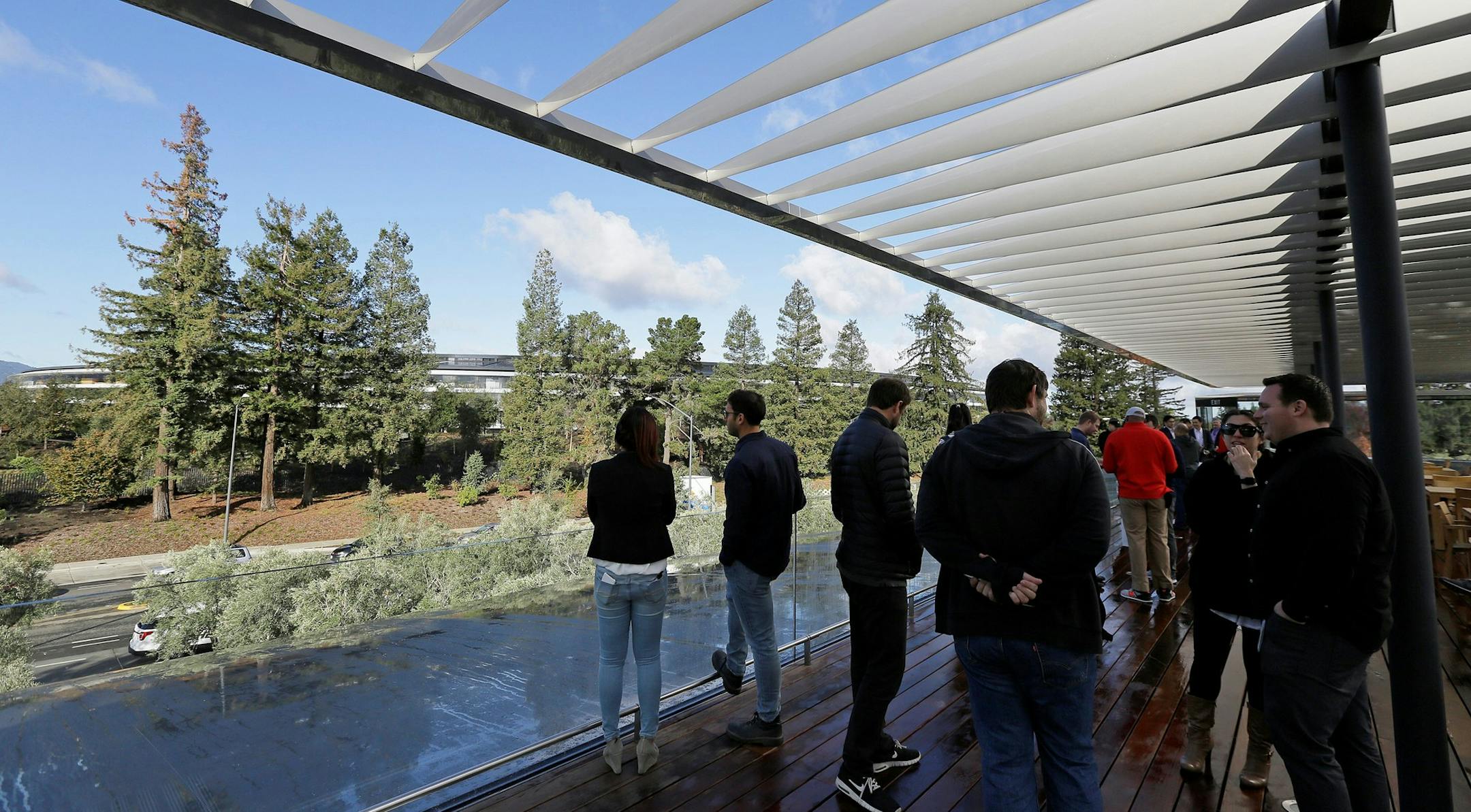 People stand on a rooftop terrace with the main building in the background during the grand opening of the Apple Park Visitor Center Friday, Nov. 17, 2017, in Cupertino, Calif. (AP Photo/Eric Risberg) ORG XMIT: OTK