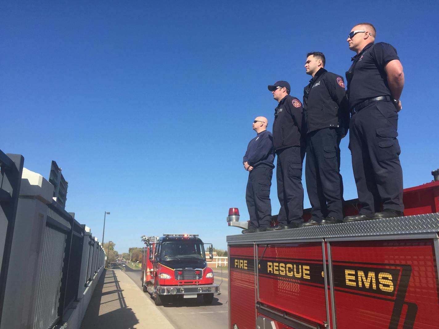 Members of the Brooklyn Park Fire Dept. stand atop their trucks over I-94 to salute the procession carrying the body of slain Sheriffs Deputy from St. cloud en route to Ramsey Co.