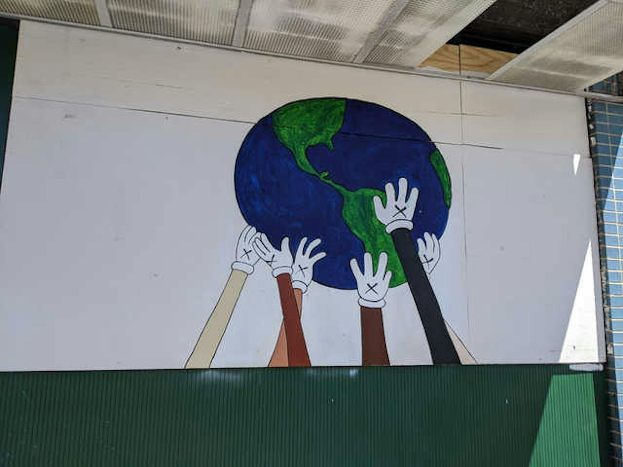 In the wake of George Floyd's death by police, sneaker designer Salvatore Marcum took to the streets, painting a mural of hands holding up the world on the front of Green Machine at 2409 Nicollet Ave.