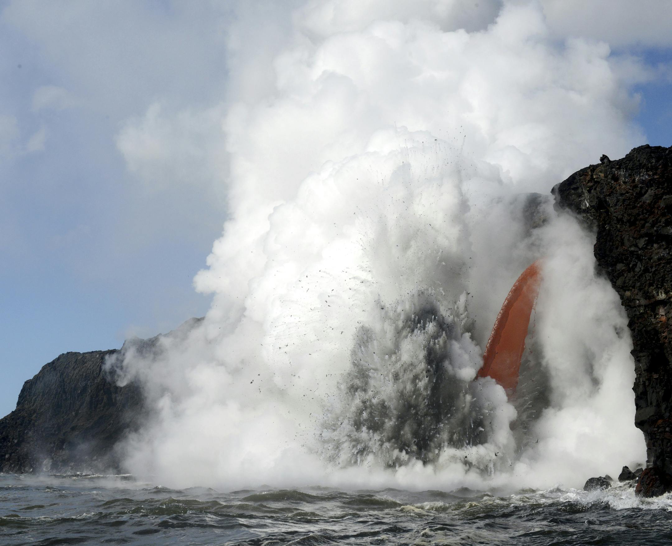 A “firehose” lava stream from Kilauea Volcano shot out from a sea cliff.
